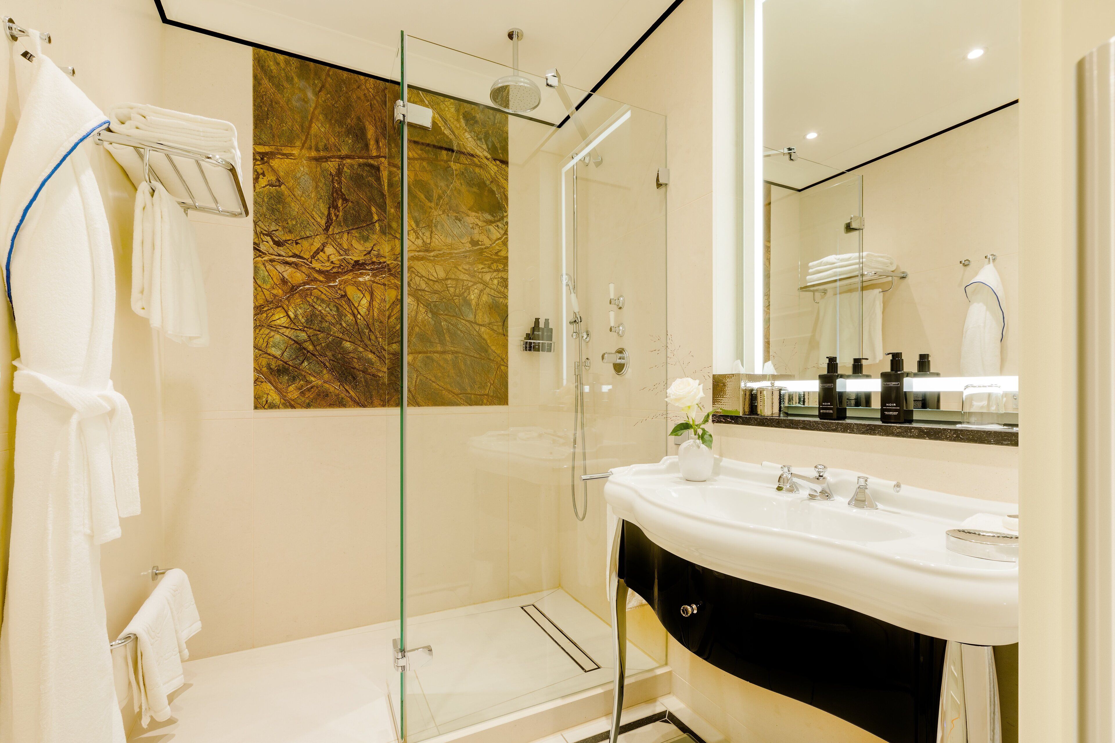 A modern bathroom with a glass-enclosed shower, a white sink, and a large mirror.