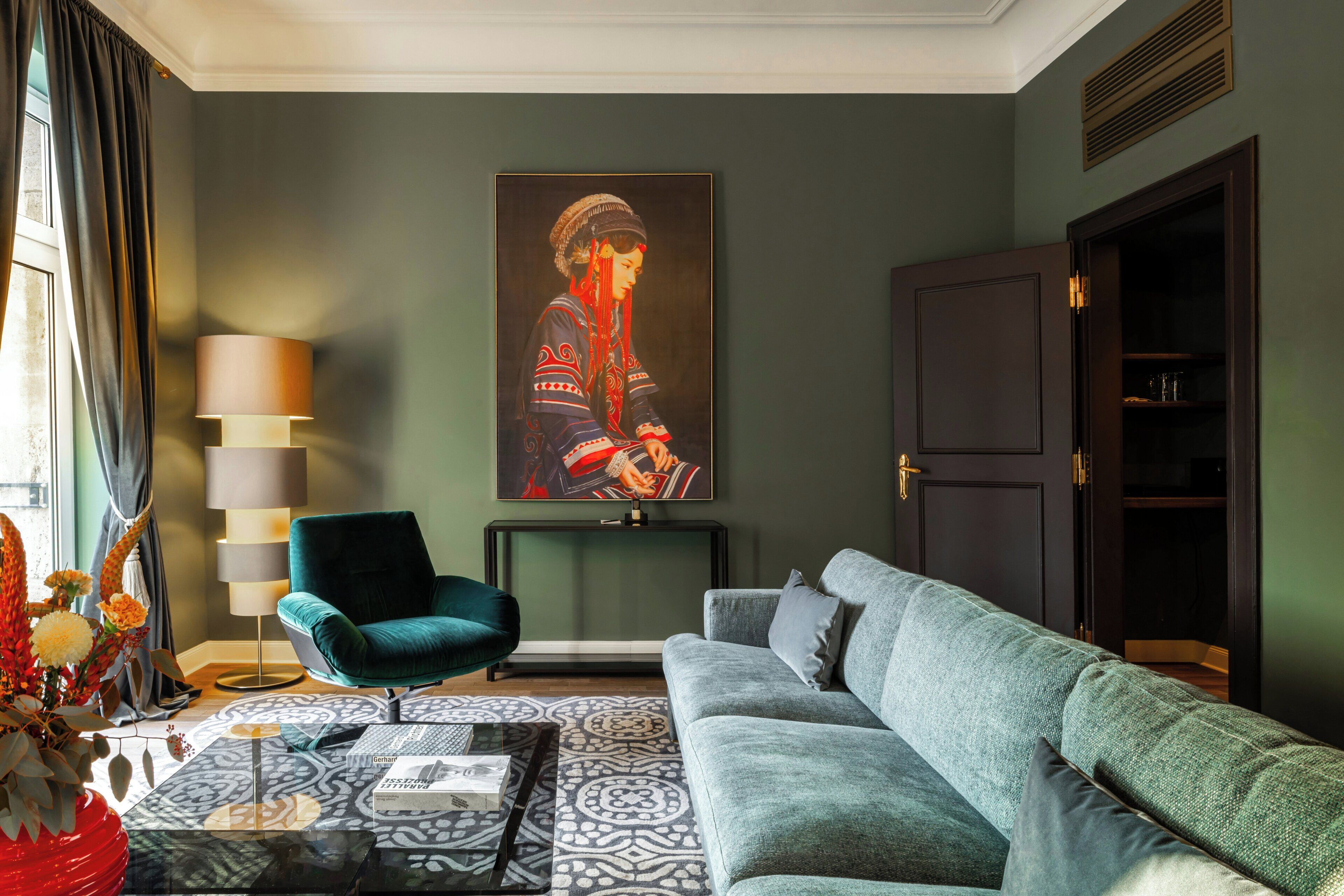 Een woonkamer met een bank, fauteuil, salontafel en een schilderij aan de muur.