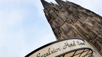Das Schild des Hotels Excelsior Ernst mit gotischer Architektur im Hintergrund.