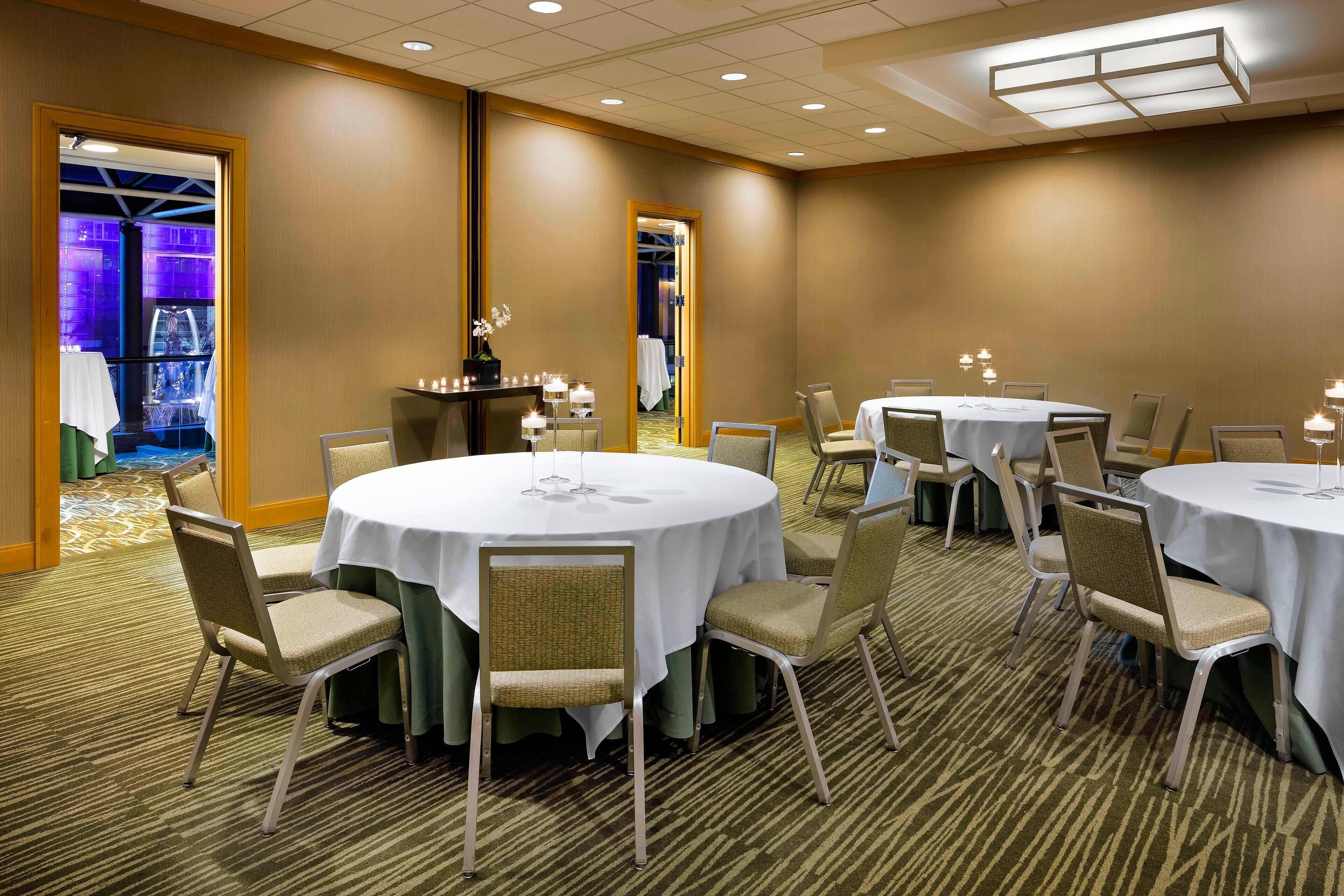 A conference room with round tables, chairs, and a carpeted floor.
