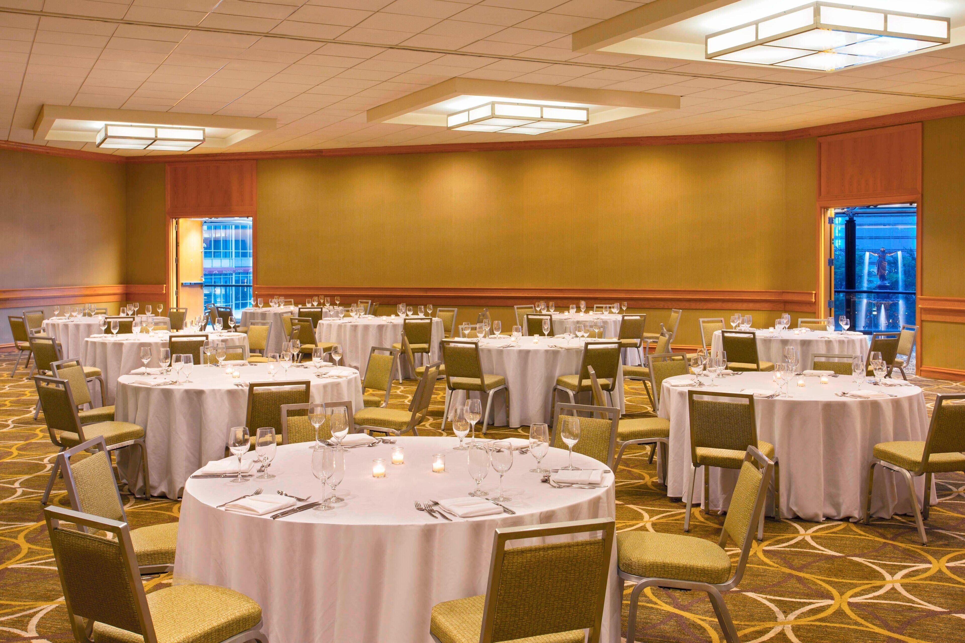 A banquet hall with round tables set for dining, each with chairs and table settings.