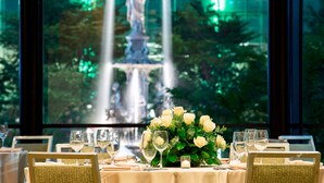 Une table à manger décorée de roses blanches, de verres à vin et ornée d’une statue en arrière-plan.
