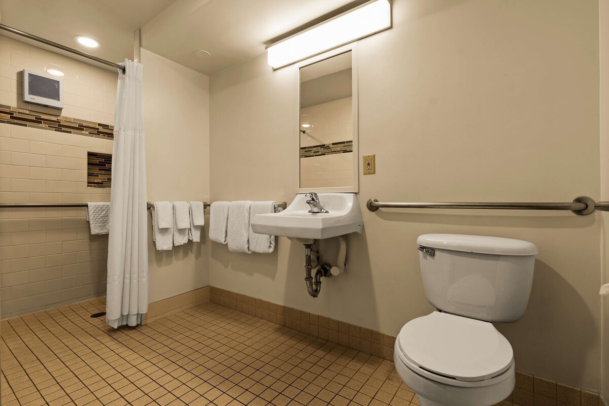 Un baño con lavamanos blanco, inodoro, cortina de ducha y espejo.