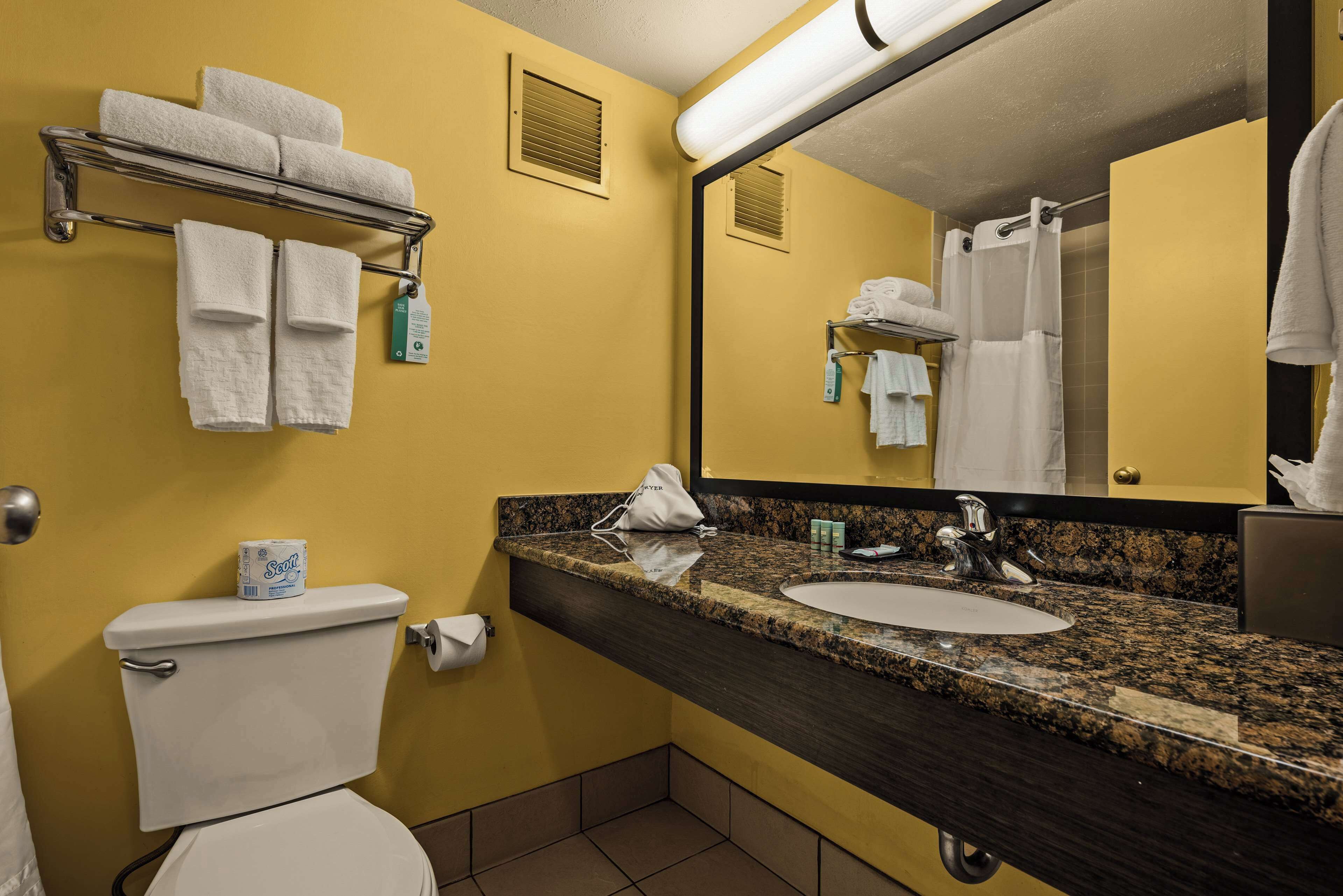 Baño con inodoro, lavamanos y barra para toallas.