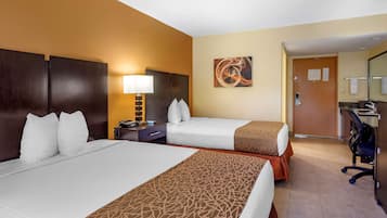 A hotel room with two beds, a desk, a chair, a lamp, and a painting on the wall.
