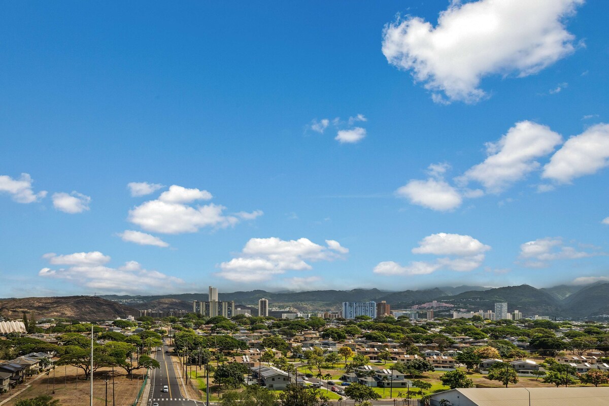 Un paisaje urbano con cielo despejado, zonas residenciales y montañas a lo lejos.