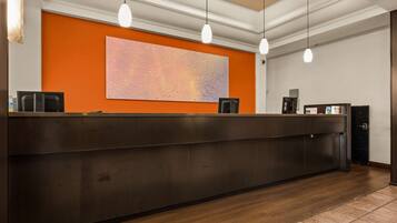 A reception desk with a dark wood finish, a large abstract painting on the wall, and pendant lighting.
