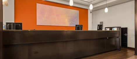 A reception desk with a dark wood finish, a large abstract painting on the wall, and pendant lighting.