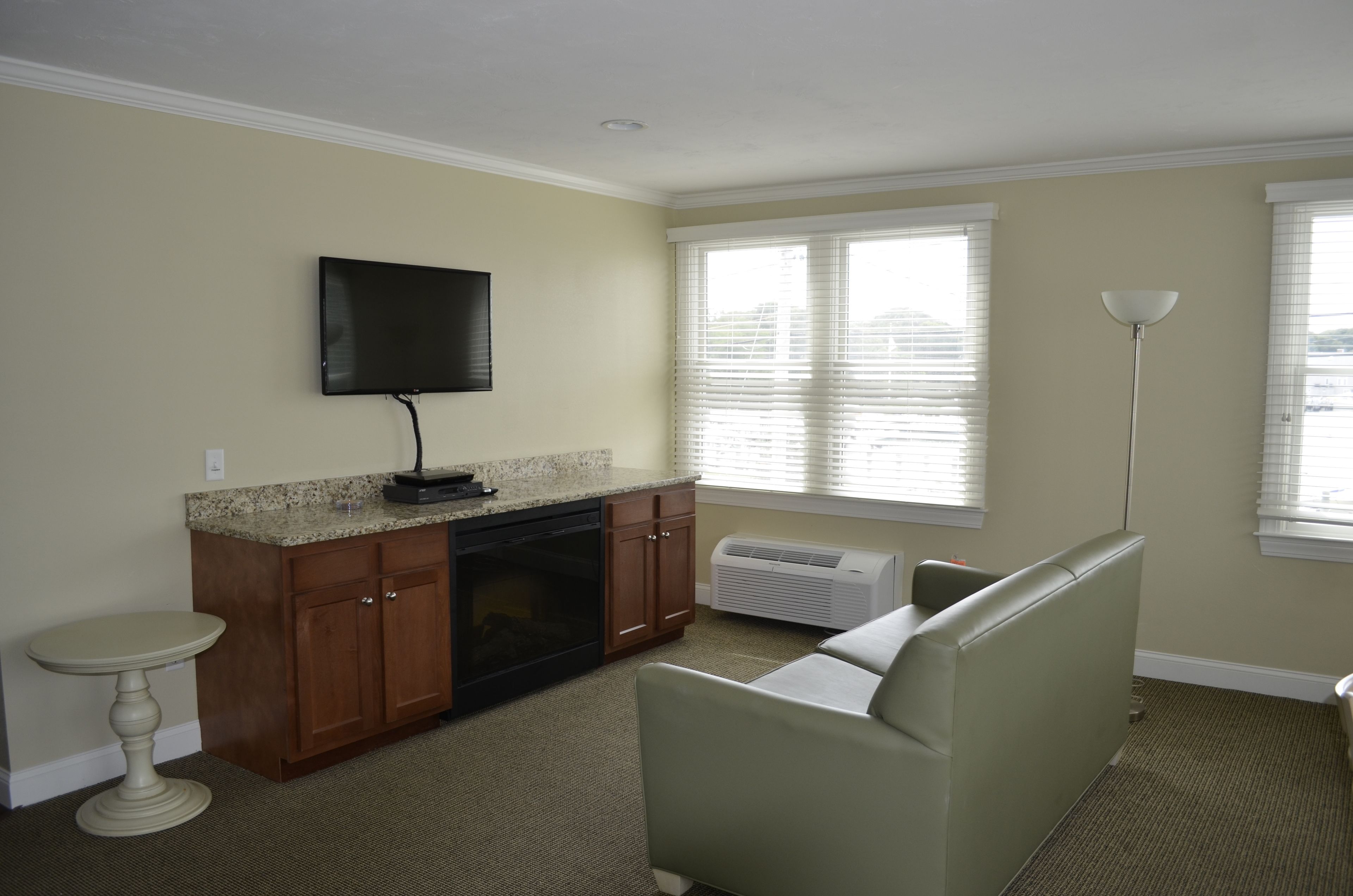 A living room with a sofa, a television, a small table, and a window with blinds.