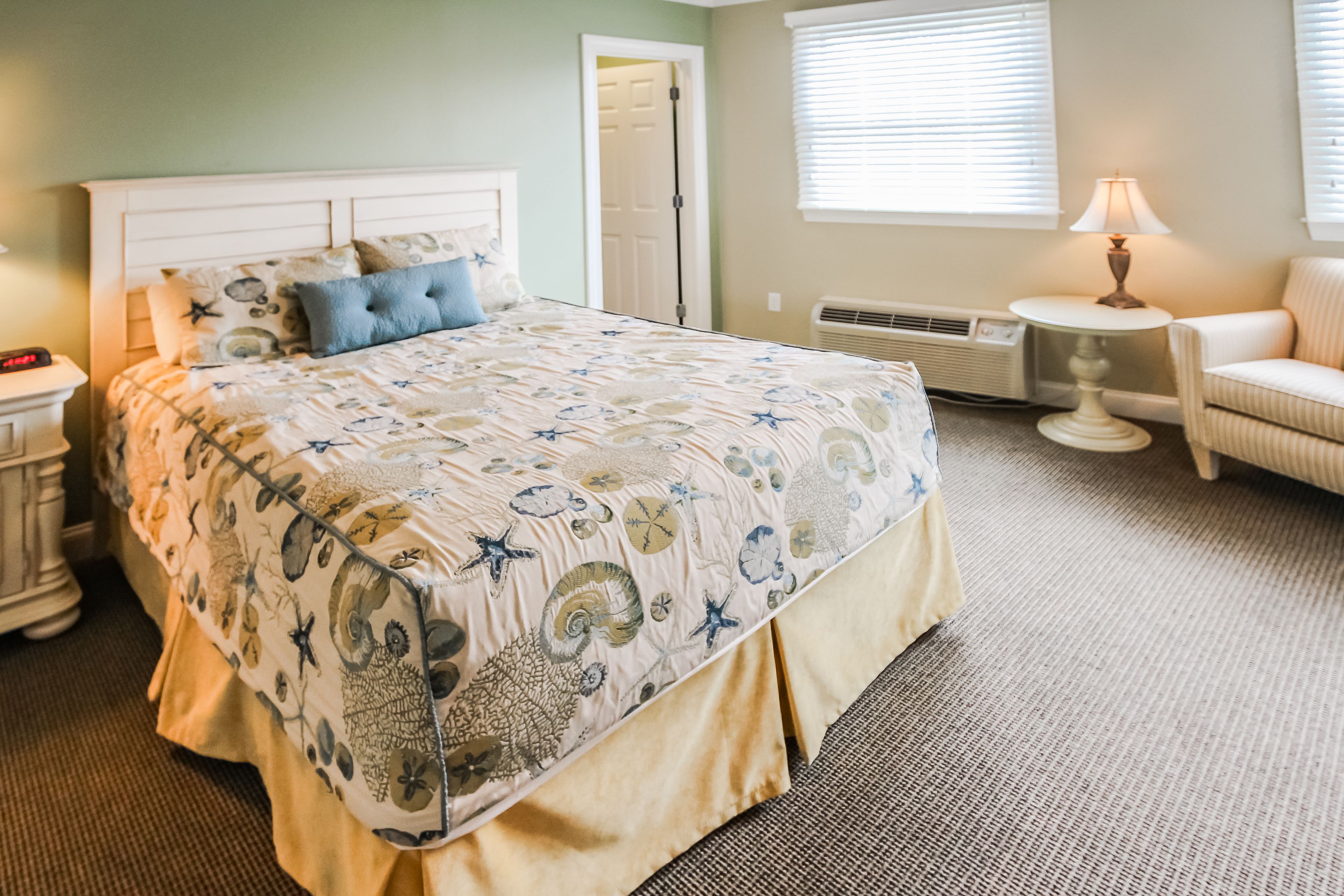 A bedroom with a bed, bedside tables, a chair, a lamp, and a door.