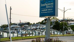 En skylt för InnSeasons Resorts Harbor Walk, med en småbåtshamn i bakgrunden.