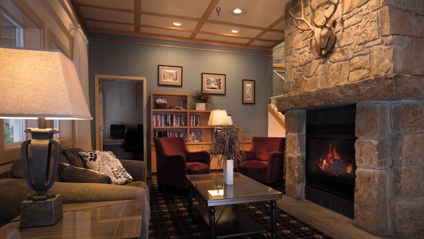A cozy living room with a fireplace, comfortable seating, and a bookshelf.