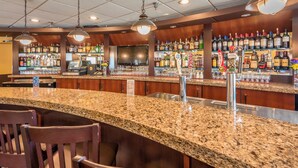 A bar area with granite countertops, bar stools, and a variety of liquor bottles.