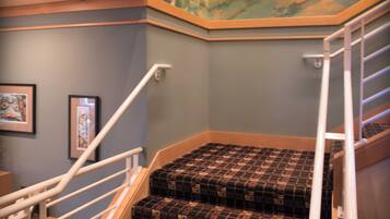 A staircase with patterned carpet and a mural on the wall above.