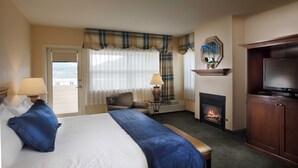 A hotel room with a bed, a television, a fireplace, and a view of the outside.