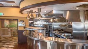 A modern kitchen with stainless steel appliances, a curved counter, and overhead lighting.