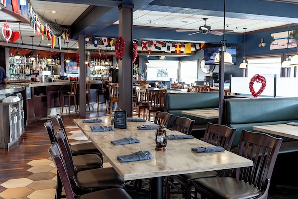 Un interior de restaurante con una zona de bar, cabinas y vista a la calle.