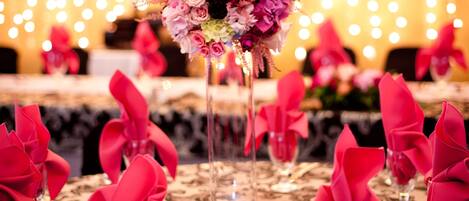 Une table dressée avec des serviettes roses et un arrangement floral en guise de décoration centrale.