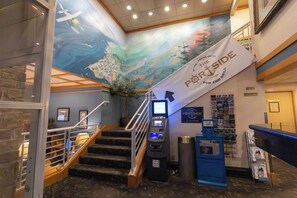 A hotel lobby with a mural, a banner for the Portside Pub and Grill, a staircase, and an ATM. - The Landing Hotel & Restaurant (Ketchikan)