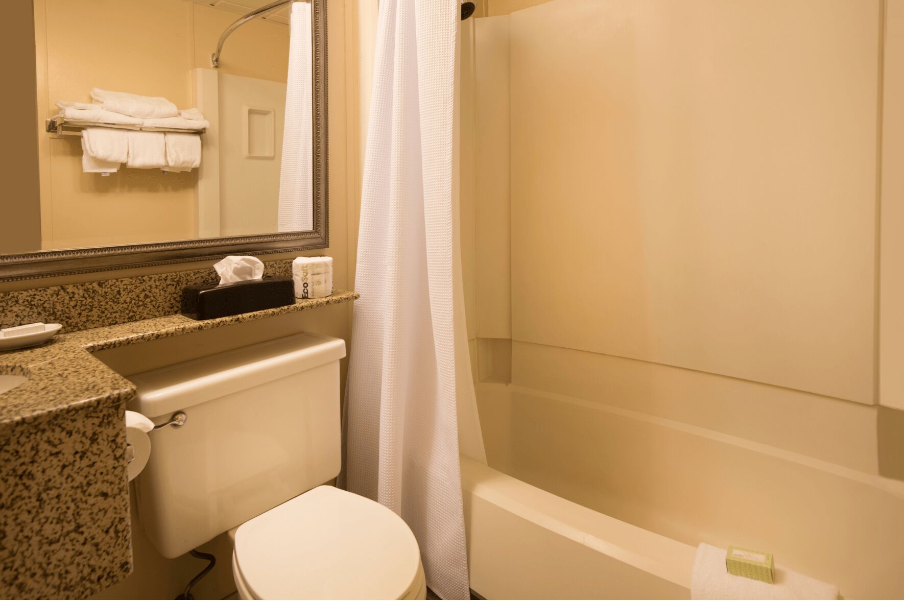 A bathroom with a toilet, sink, and bathtub. There is a towel rack with towels and a mirror above the sink.