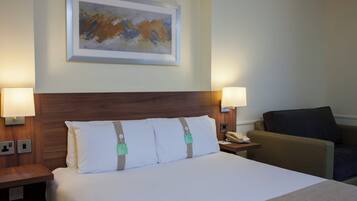 Habitación de hotel con una cama grande, dos lámparas de noche, un teléfono, una silla y un cuadro en la pared.