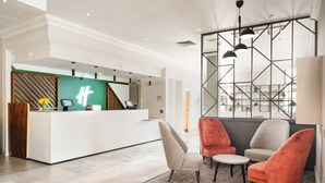 A modern reception area with a reception desk, seating area, and a view of the interior. - Holiday Inn Leeds Wakefield M1 Jct.40 by IHG (Ossett)