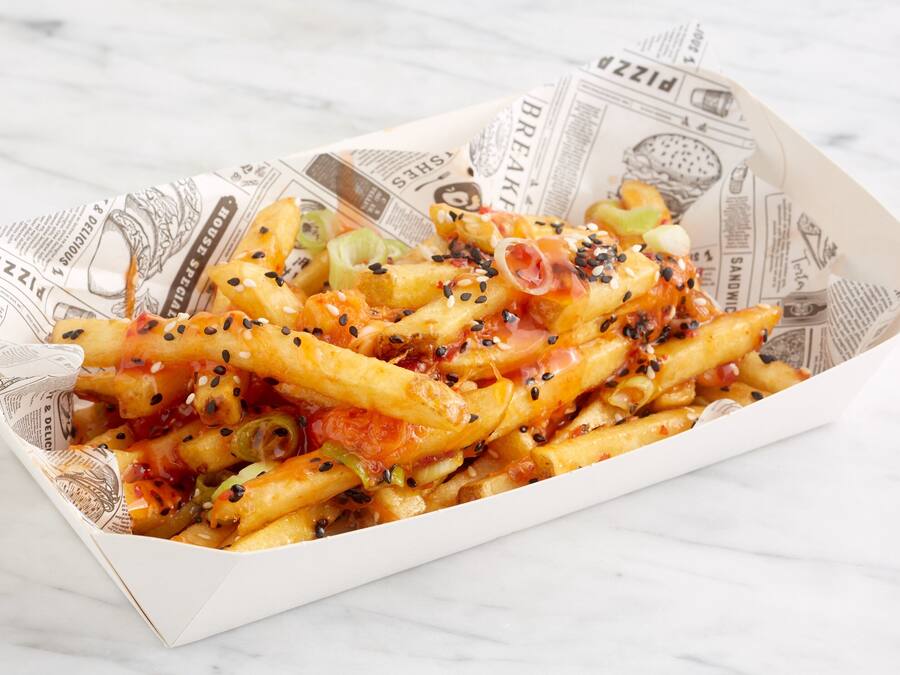 Een doos frieten met verschillende toppings, op een marmeren oppervlak.