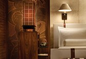 A room with a wooden cabinet, a bedside table with a lamp, and a bed with pillows.