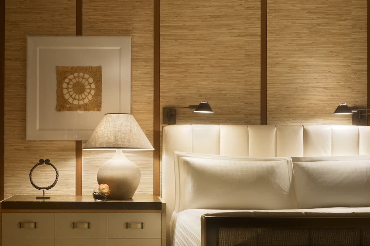 Ein Schlafzimmer mit einem Bett, einem Nachttisch, einer Lampe und einem gerahmten Bild an der Wand.