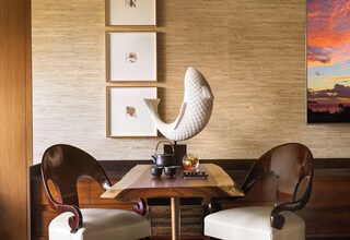 A dining area with a wooden table, two chairs, and a decorative sculpture.
