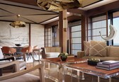 A modern living room with a clear glass coffee table, leather sofas, and a unique ceiling light fixture.