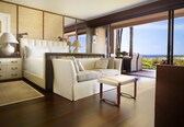 A modern bedroom with a large bed, a sofa, and a view of the ocean.