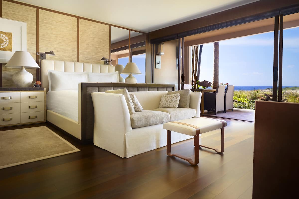 Ein modernes Schlafzimmer mit einem großen Bett, einer Couch und Blick auf den Ozean.