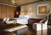 A hotel room with a bed, bedside tables, a desk, a chair, and a ceiling fan.