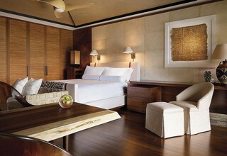 A hotel room with a bed, bedside tables, a desk, a chair, and a ceiling fan.