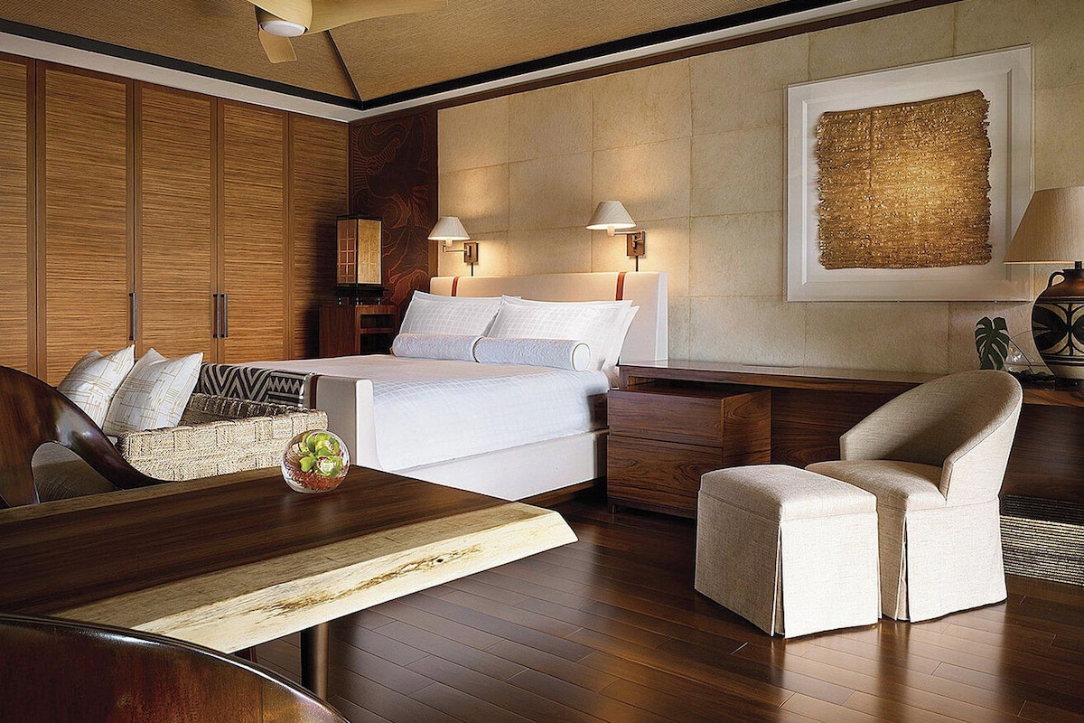 A hotel room with a bed, bedside tables, a desk, a chair, and a ceiling fan.