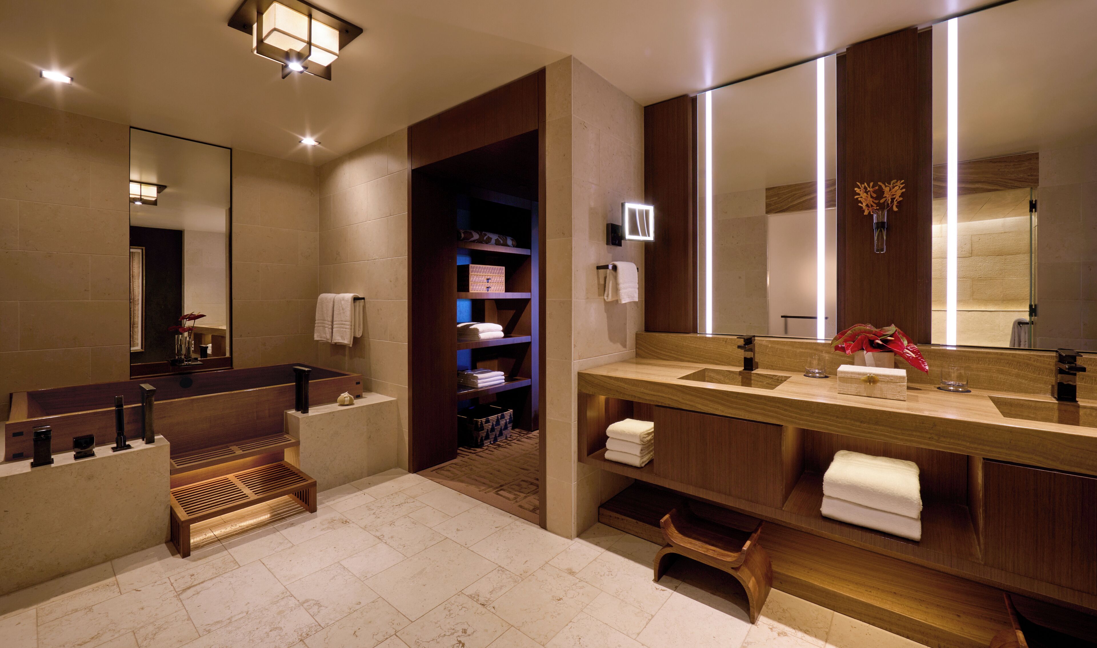 Un baño moderno con un espejo grande, lavamanos dobles y un banco incorporado.
