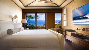 Un dormitorio amplio con una cama grande, un ventilador de techo, vista al océano y un comedor con vistas.