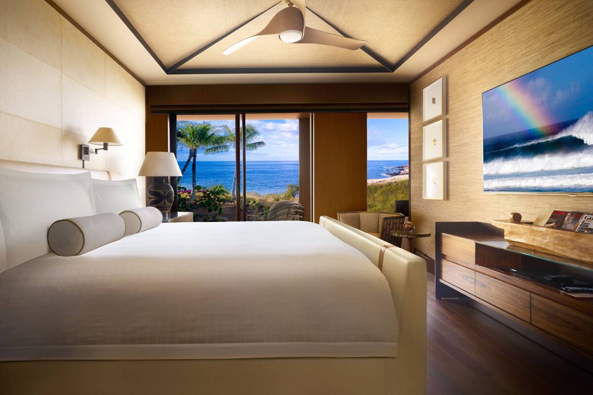 Ein geräumiges Schlafzimmer mit einem großen Bett, einem Deckenventilator, Meerblick und einem Essbereich mit Aussicht.