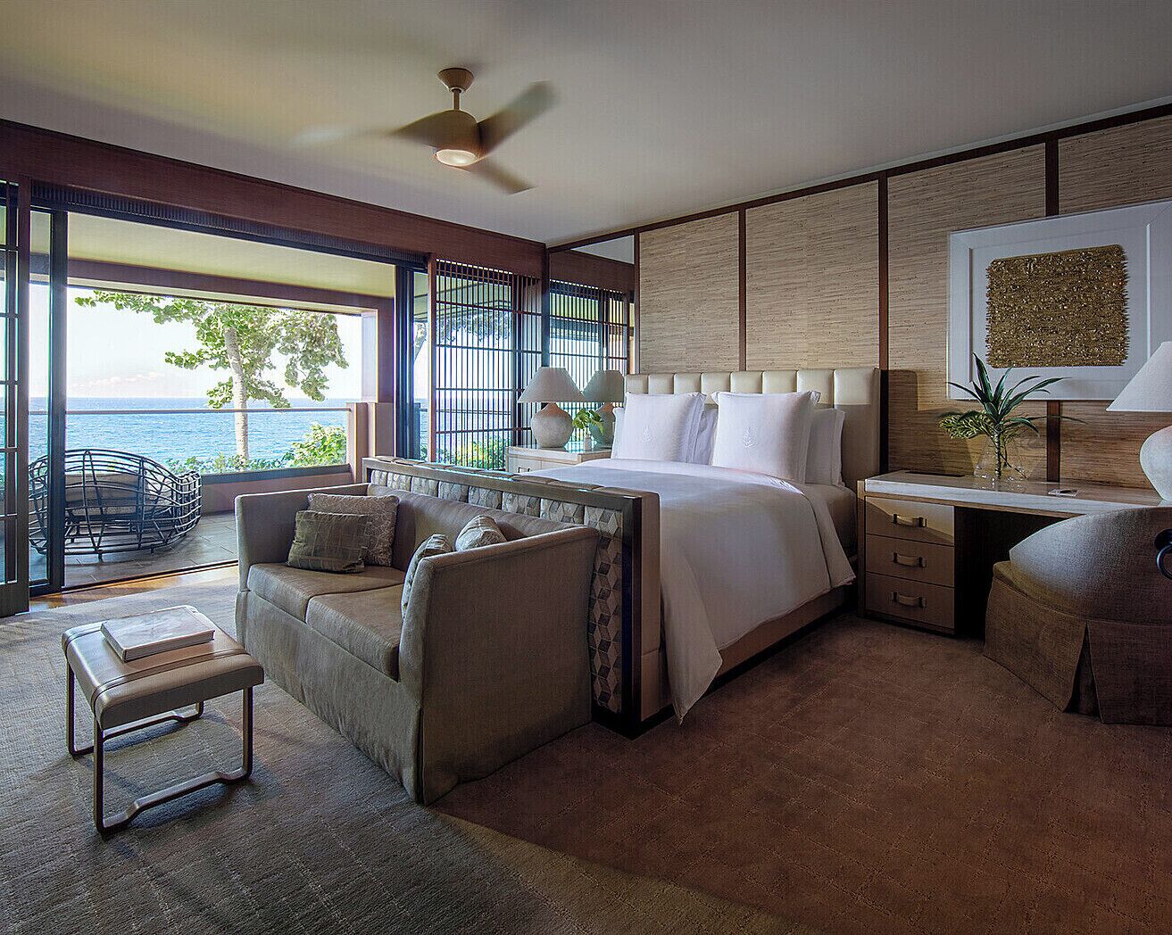 Quarto moderno com uma cama grande, um espaço de estar e uma escrivaninha.