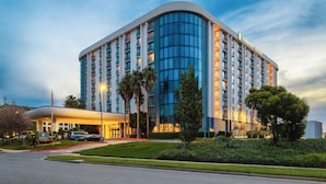 A modern hotel with a curved facade, multiple floors, and a well-lit entrance.