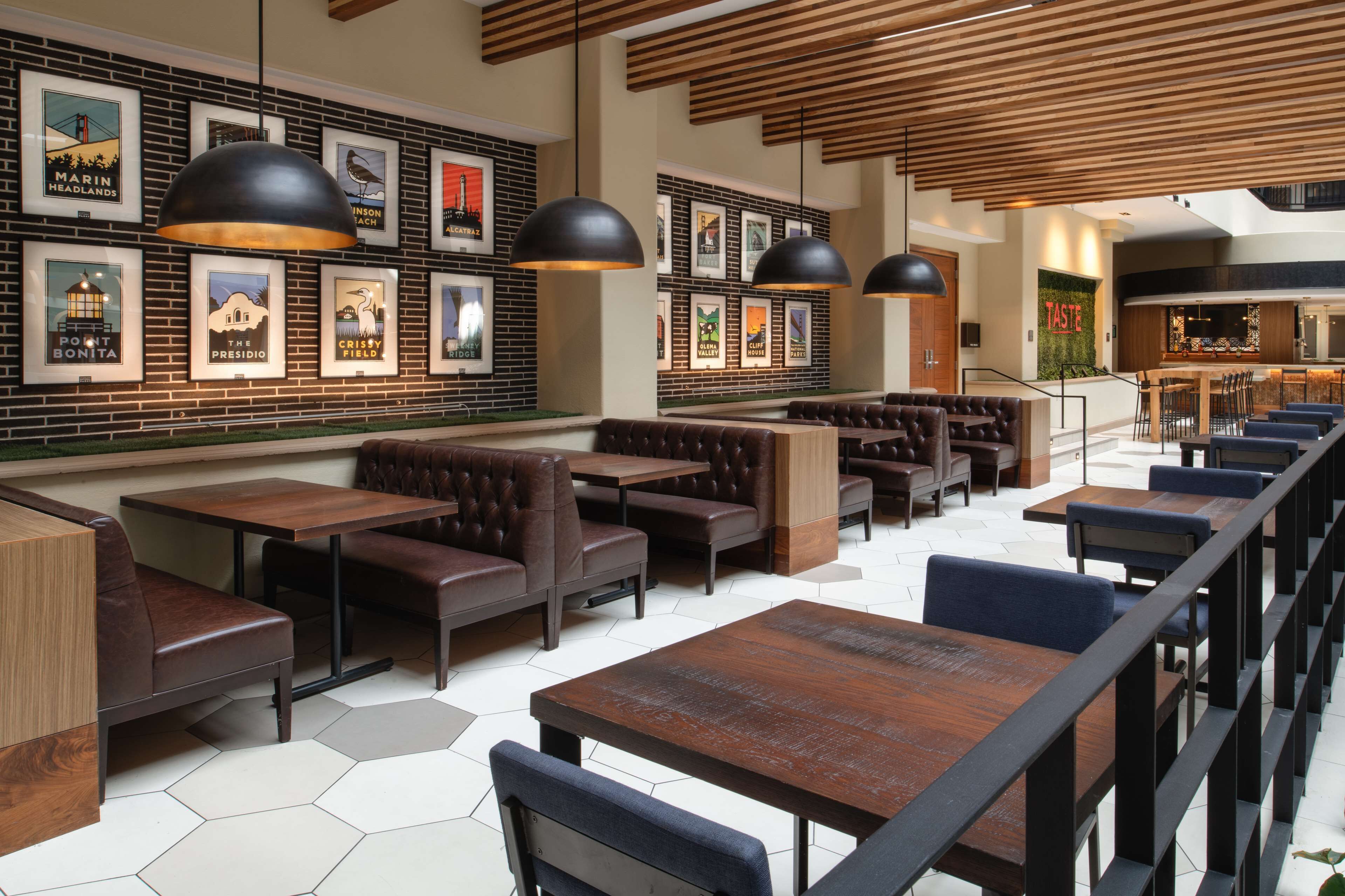 Un restaurant doté d’un sol carrelé à motifs hexagonaux, de tables et de bancs en bois, et de tableaux encadrés accrochés aux murs.