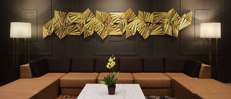 A modern living room with a sectional sofa, a marble coffee table, and a decorative wall piece.
