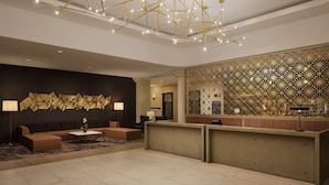 A modern lobby with a reception desk, seating area, and decorative wall panels.