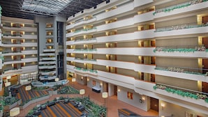 A multi-level hotel atrium with balconies, seating areas, and a central column. - Holiday Inn University Plaza-Bowling Green by IHG (Bowling Green)