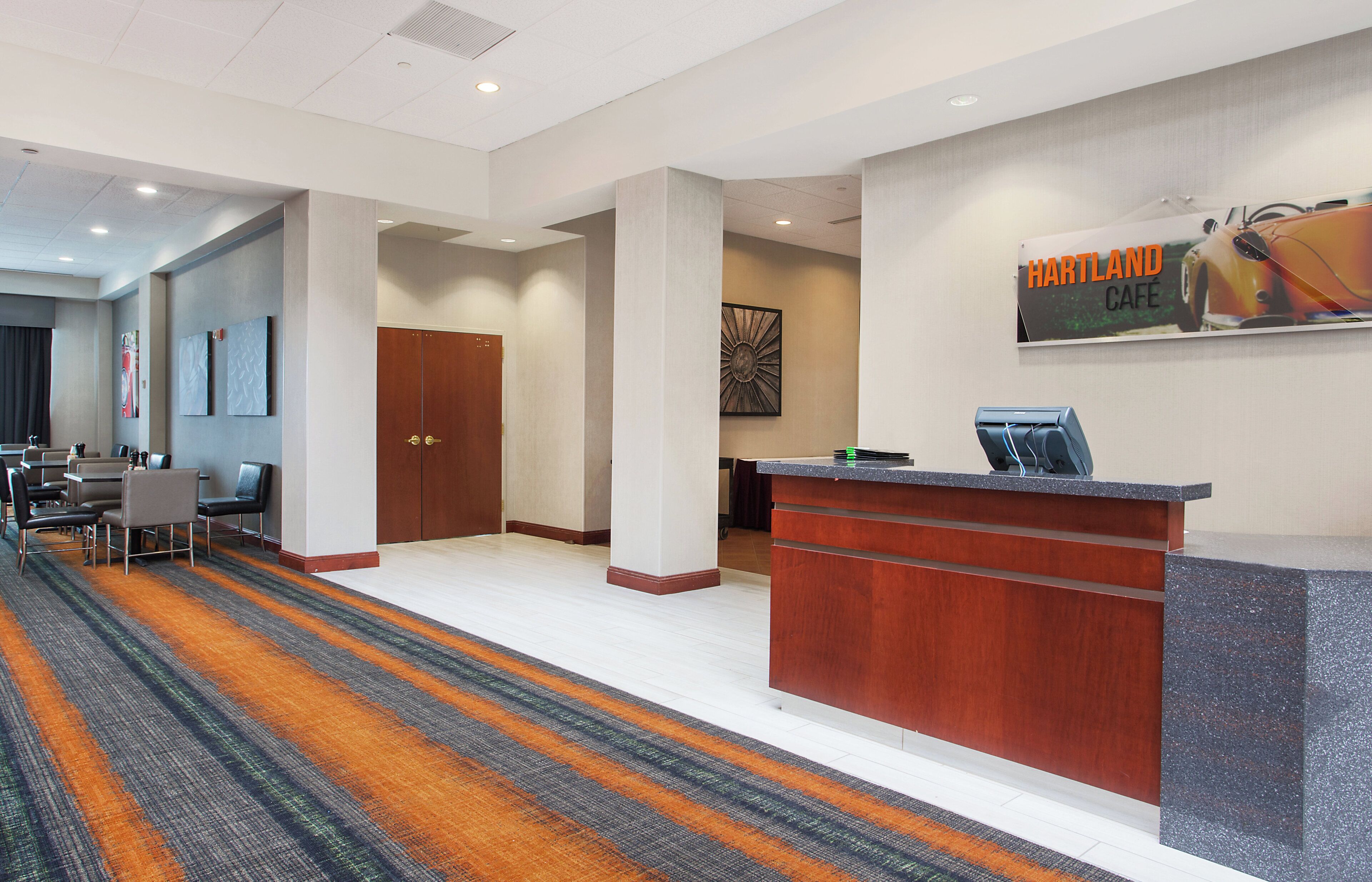 A hotel lobby with a reception desk, seating area, and a sign for the Hartland Cafe.