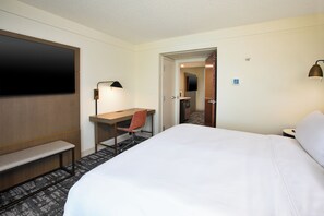 Una habitación de hotel con cama, escritorio, silla y televisión.