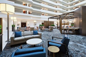 A spacious hotel lobby with multiple seating areas, a reception desk, and a high ceiling with natural light. - Crowne Plaza Bowling Green KY by IHG (Bowling Green)