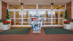 A building entrance with double doors, a decorative car sculpture, and potted plants. - Holiday Inn University Plaza-Bowling Green by IHG (Bowling Green)