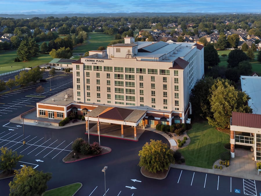 Un grand hôtel doté d’un parking et, en arrière-plan, d’un terrain de golf.